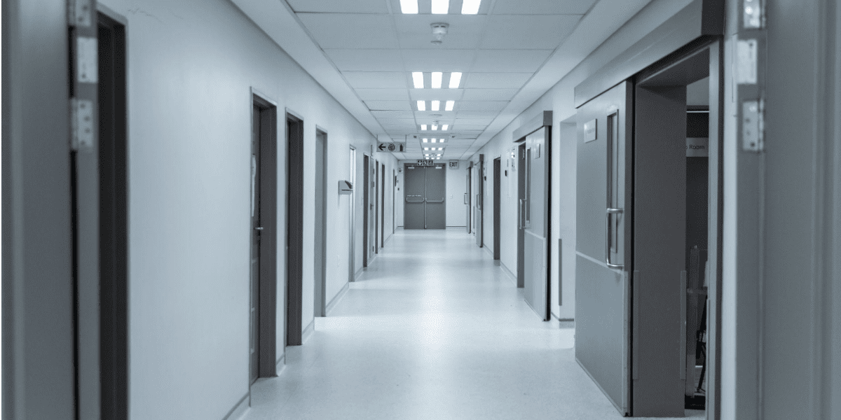 Empty hospital corridor with clinical lighting, conveying a serious medical setting
